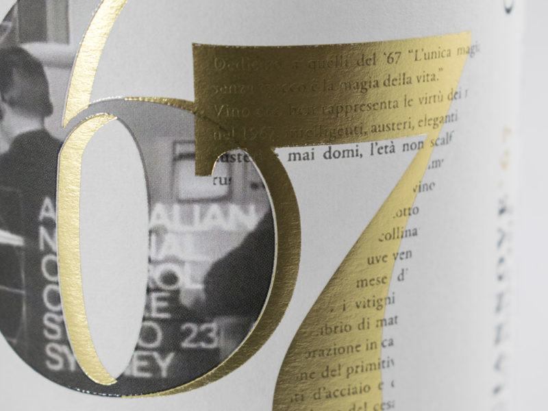 Closeup di una etichetta di vino rosso con lamina oro, rilievo serigrafico e carta bianca su sfondo bianco